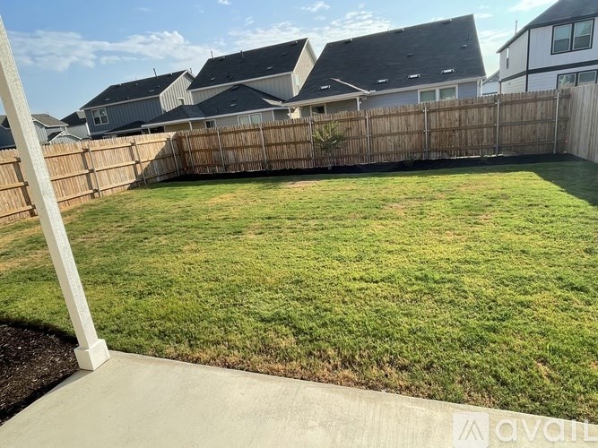 A backyard with a wooden fence and a well-maintained lawn.