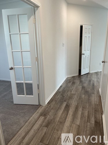 A hallway with a white door and a white door with a black handle.