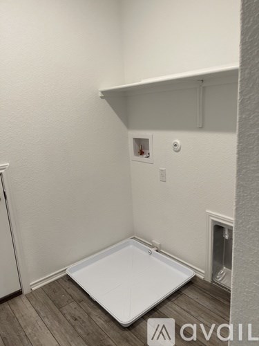 A small white bathtub in a room with white walls and wooden flooring.
