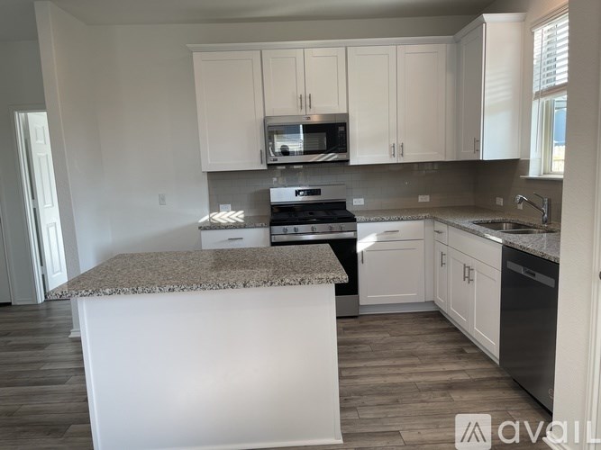 A kitchen with a granite countertop and stainless steel appliances.