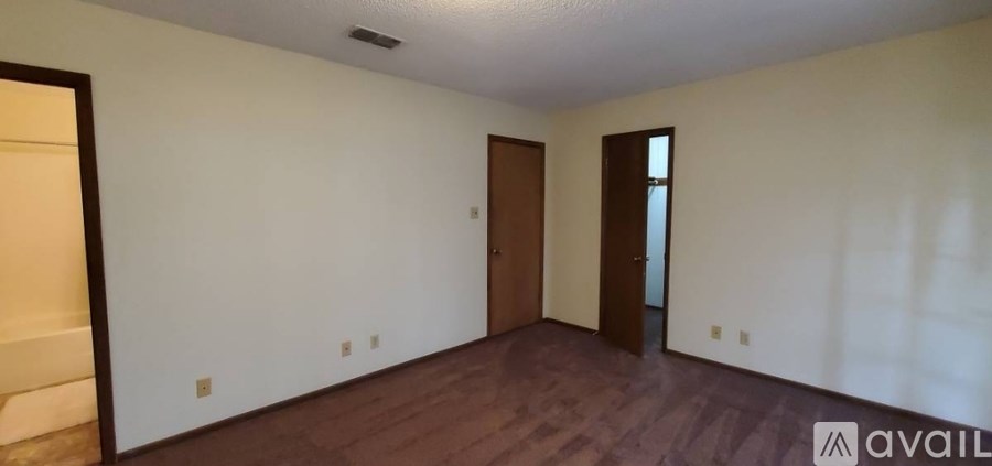 A room with wooden floors and white walls, with two doors and a window.