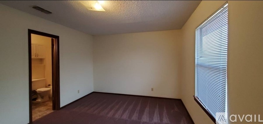 A room with a carpeted floor and a window with blinds.