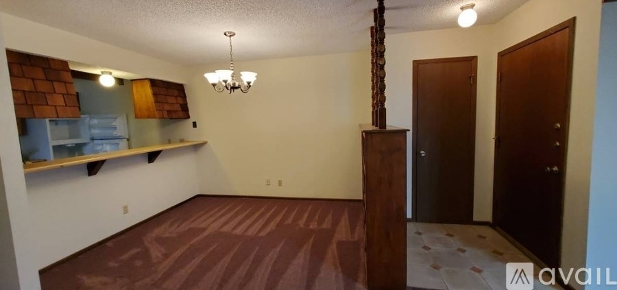 A room with a chandelier and a wooden column in the middle.