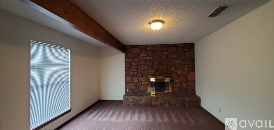 A living room with a stone fireplace and a carpeted floor.