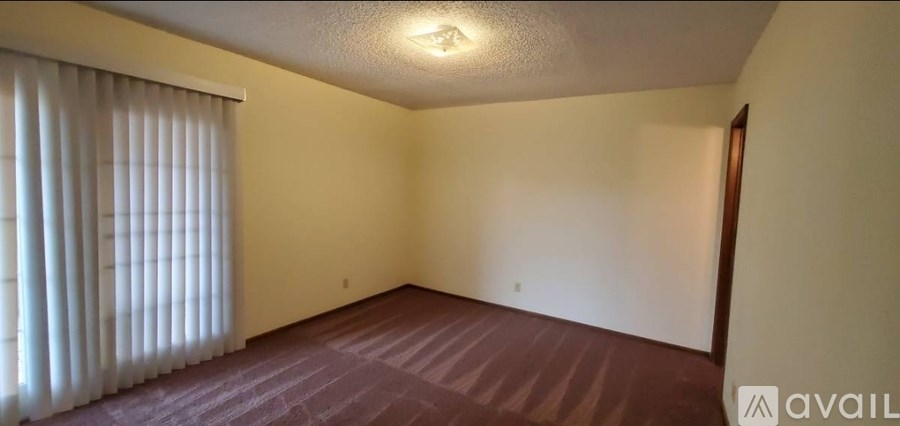 A room with a carpeted floor and a window with blinds.