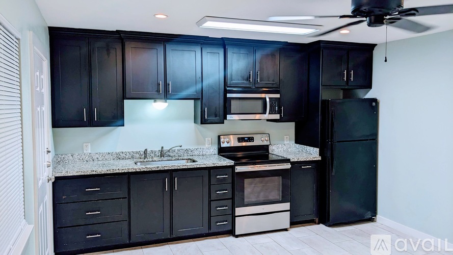 A kitchen with black cabinets and a white countertop.
