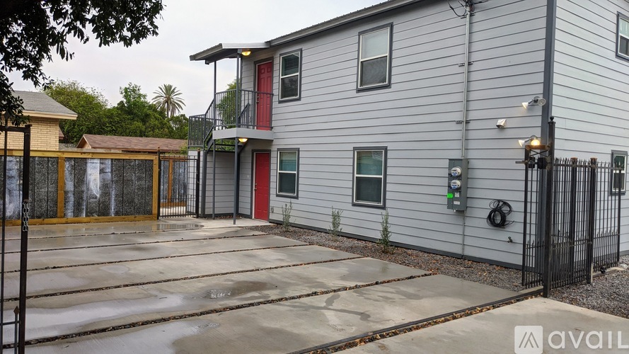 A grey building with a red door and a black fence.