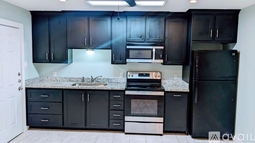 A kitchen with black cabinets and appliances.
