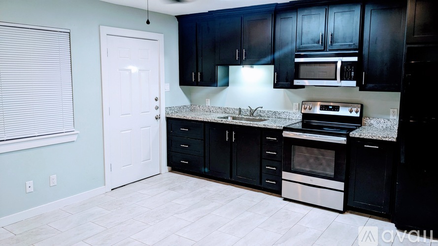 A kitchen with black cabinets and a white door.
