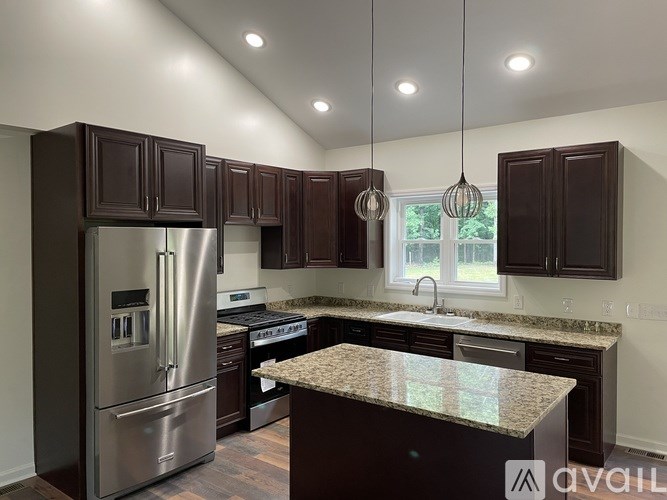 A modern kitchen with dark brown cabinets and stainless steel appliances.