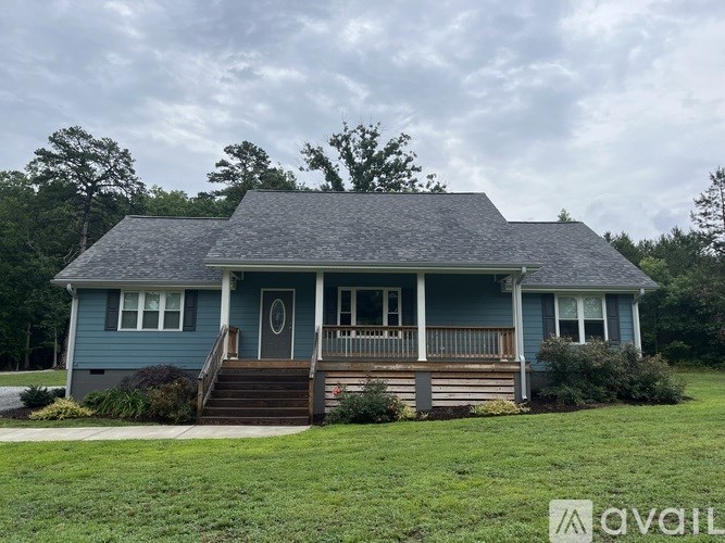 A blue house with a porch and a front yard.