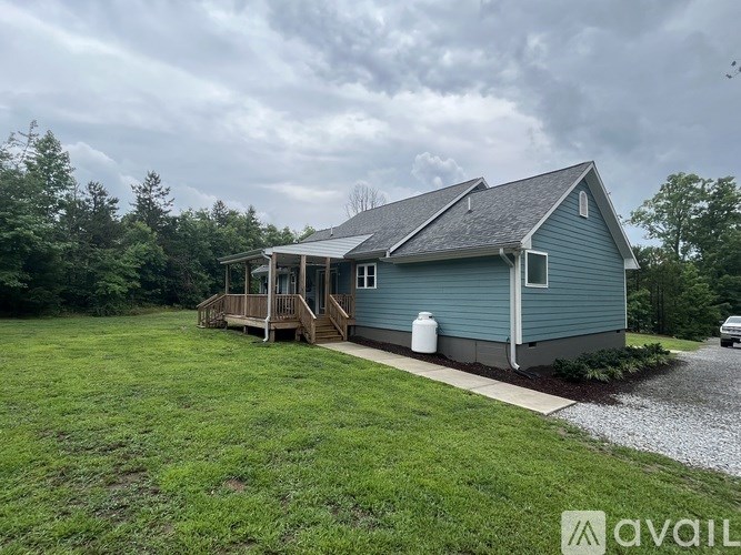A blue house with a gravel driveway in front.