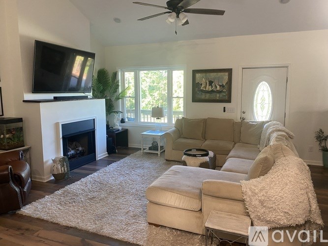 A living room with a fireplace, a couch, a chair, and a television.