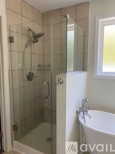 A bathroom with a glass shower stall and a white bathtub.