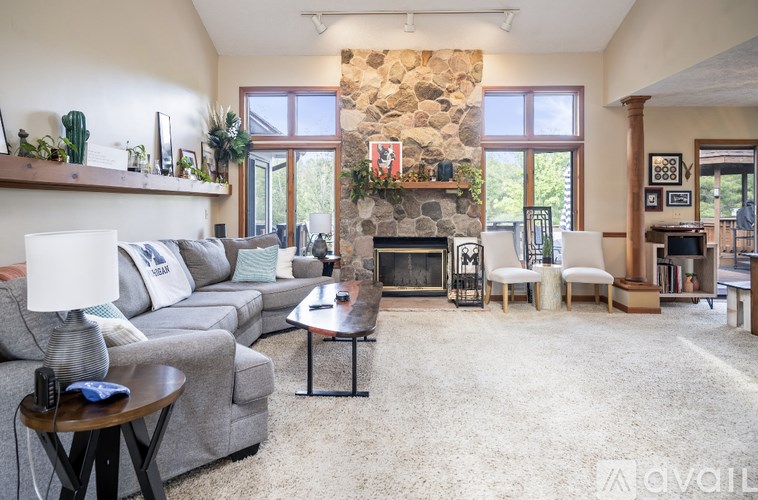 A living room with a stone fireplace and a grey couch.