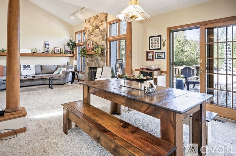 A living room with a stone fireplace and a wooden table.