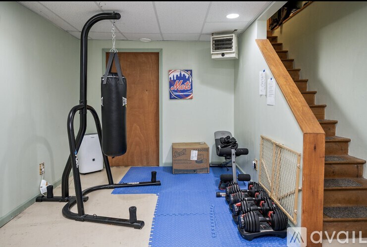 A gym room with a punching bag, exercise equipment, and a staircase.