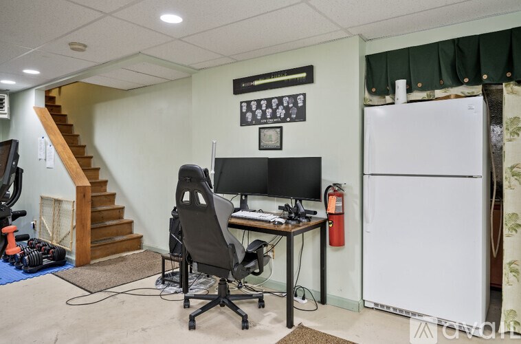 A room with a desk, computer, chair, and fire extinguisher.