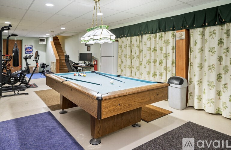 A pool table in a room with a green curtain.