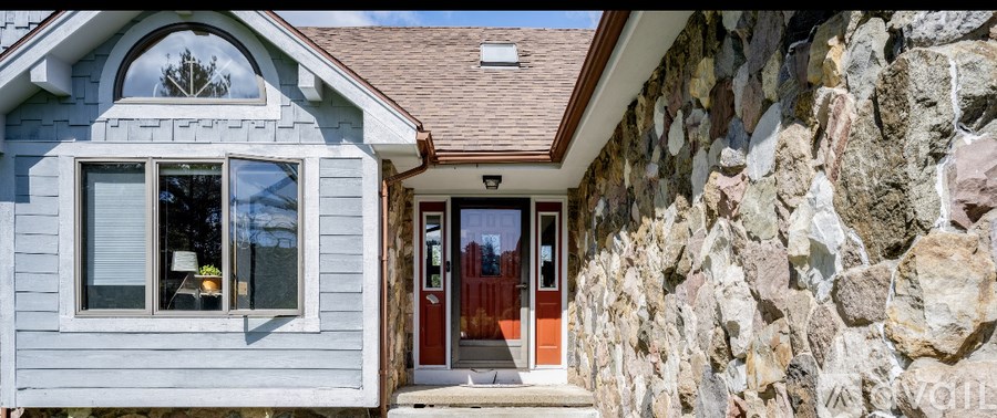 A house with a grey exterior and a red door.