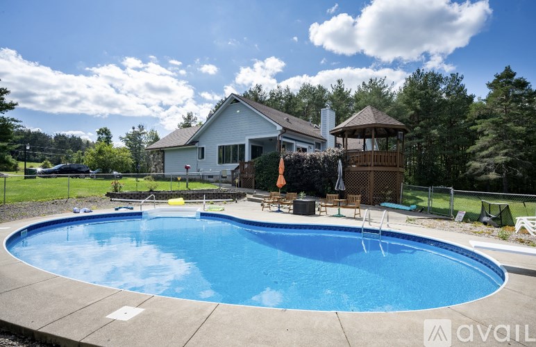 A large swimming pool in front of a house with a gazebo.