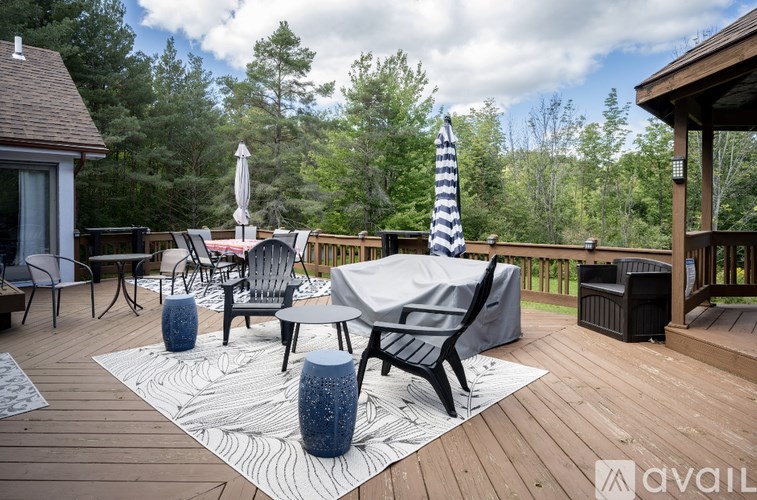 A deck with a striped umbrella and chairs.