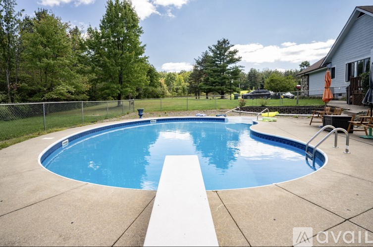 A swimming pool surrounded by a concrete patio and a white fence.