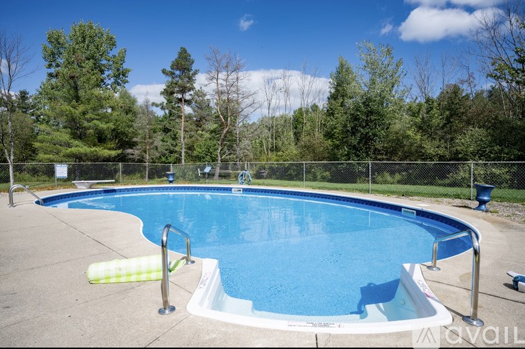 A blue swimming pool surrounded by a fence and trees.