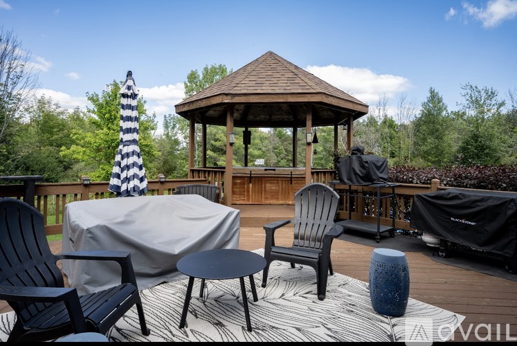 A gazebo is surrounded by a deck with chairs and umbrellas.