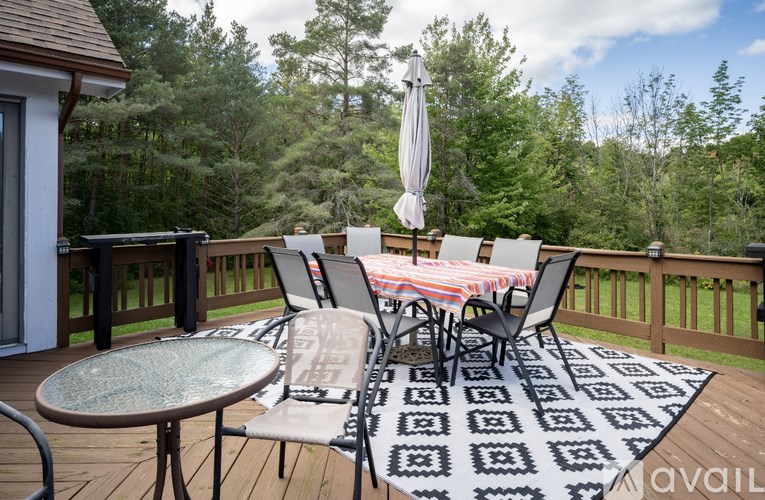 A deck with a table and chairs overlooking a forest.