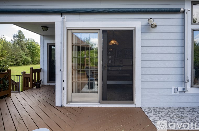 A white house with a glass door and a wooden deck.