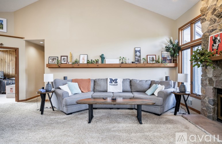 A living room with a grey couch and a stone fireplace.