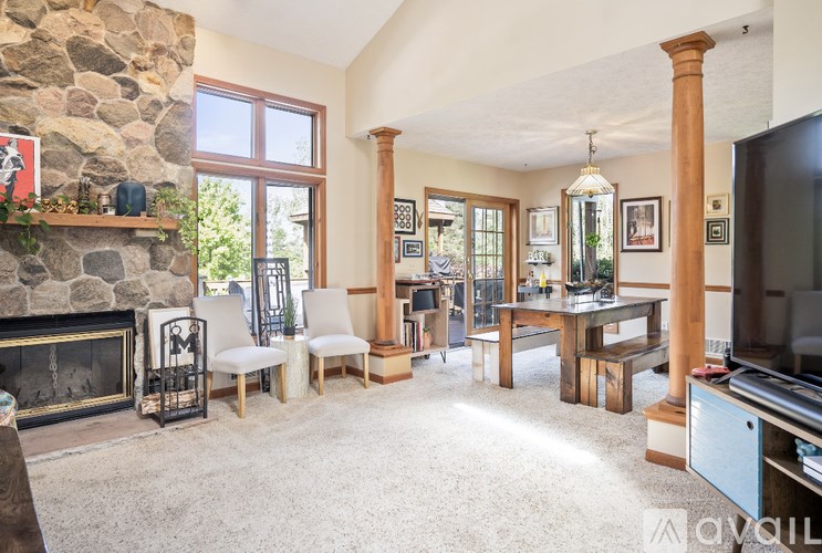 A living room with a stone fireplace and a television.