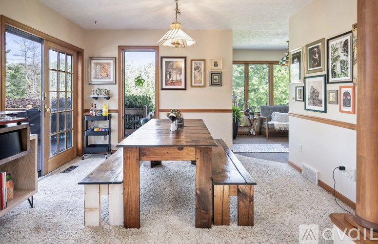 A dining room with a wooden table and bench, a chandelier, and pictures on the wall.