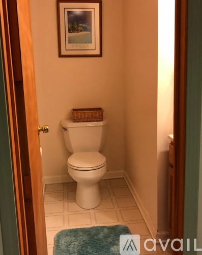 A white toilet in a small bathroom with a basket on top of it.
