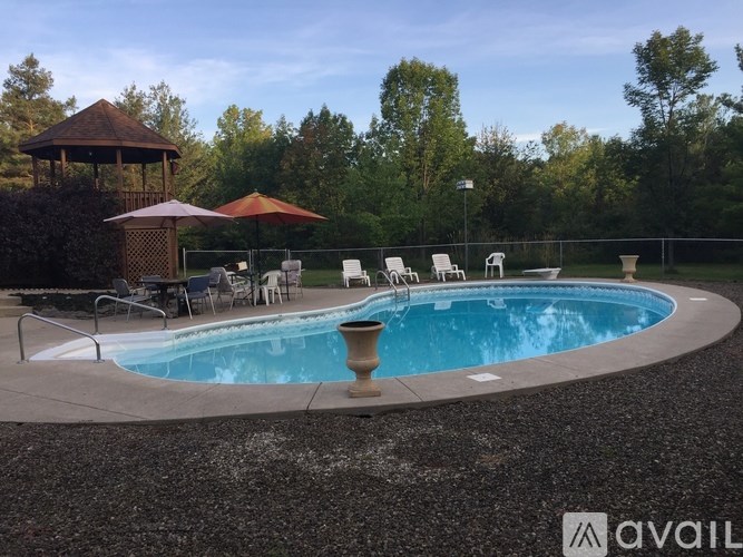 A pool with a gazebo and chairs around it.
