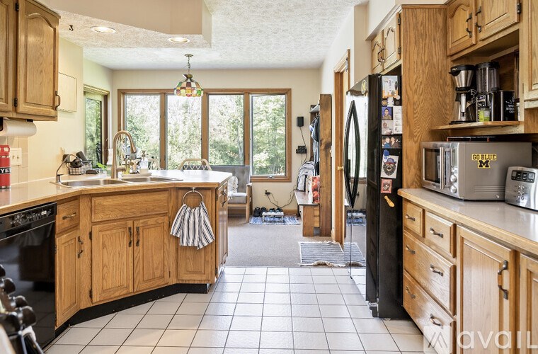 A kitchen with wooden cabinets and a black refrigerator.
