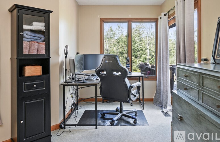 A black computer desk with a chair and a monitor.