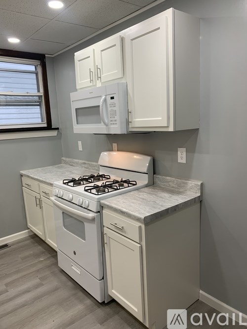 A kitchen with a white stove and cabinets.
