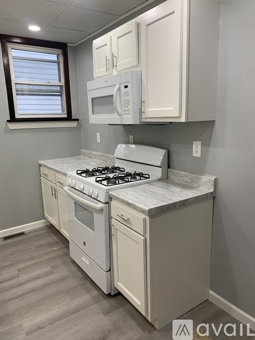 A kitchen with a white stove and cabinets.