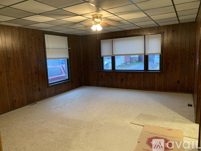 A room with wooden walls and a car parked outside the window.