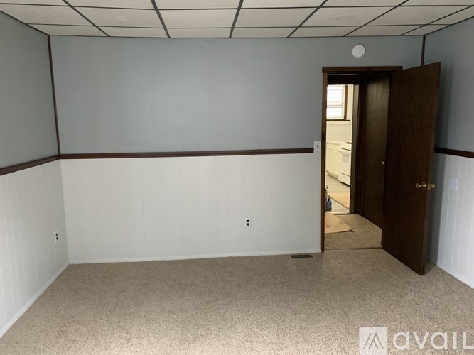 A room with a carpeted floor and a door on the right side.