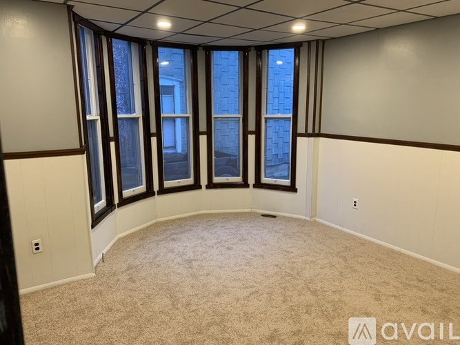 A room with a carpeted floor and large windows.