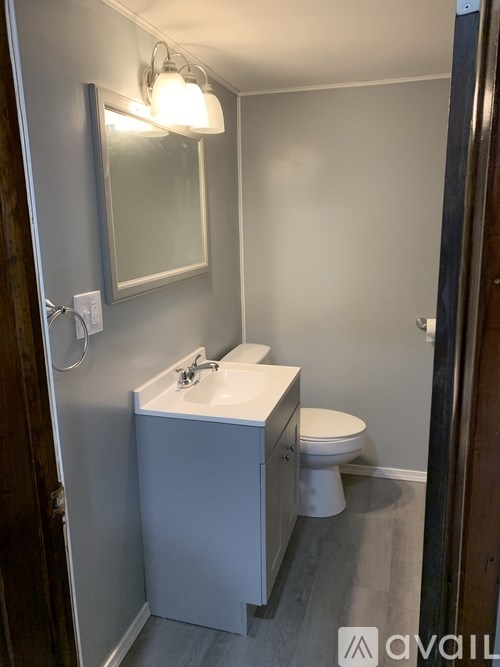 A bathroom with a toilet, sink, and mirror.