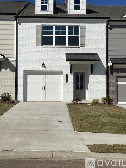 A white house with a grey roof and a black garage door.