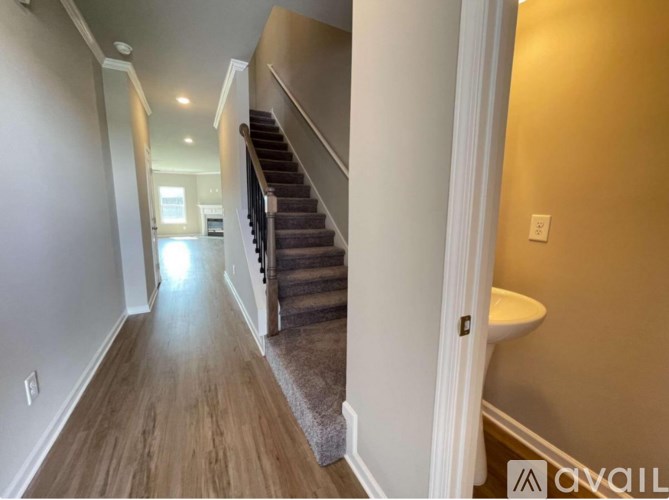 A hallway with a staircase and a toilet visible in the distance.