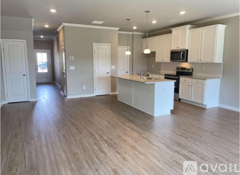 A spacious kitchen with white cabinets and a wooden floor.