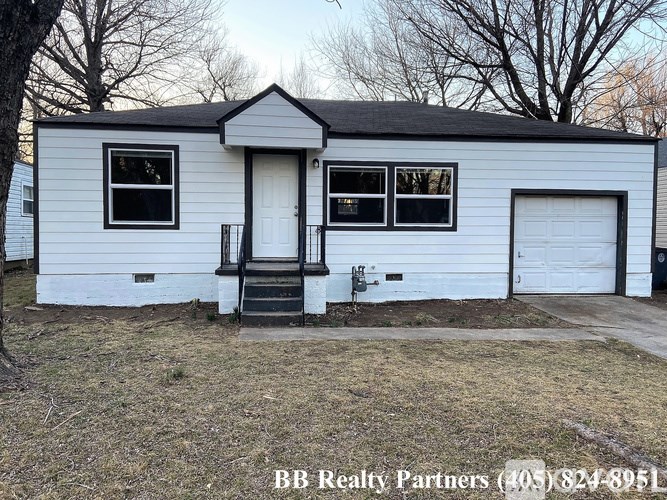 A white house with a black roof and a garage door.