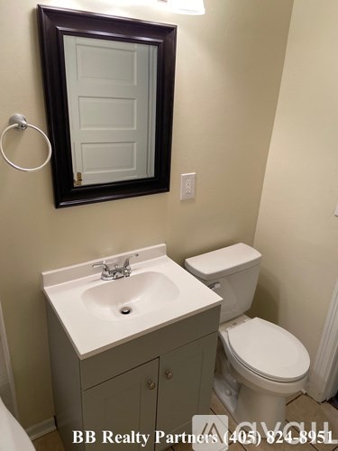 A bathroom with a toilet, sink and mirror.