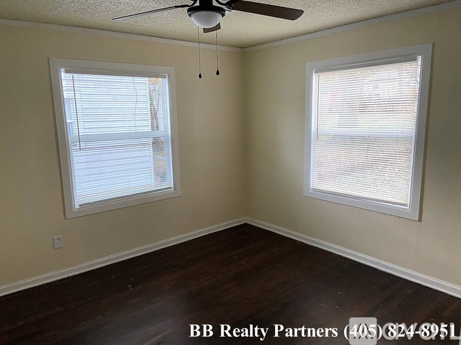 A room with a ceiling fan and two windows.
